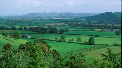 An aerial view across large expanse of countryside with trees and fields