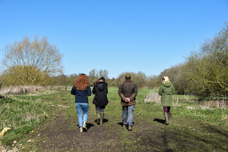 Four people walking through farmland