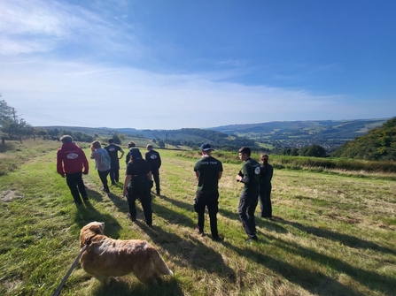 View of hills in the countryside with young people and dog walking