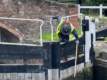 A person scrubbing dirty locks on a canal with a brush