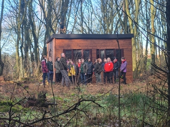 people stood in front of a small building in a forest 