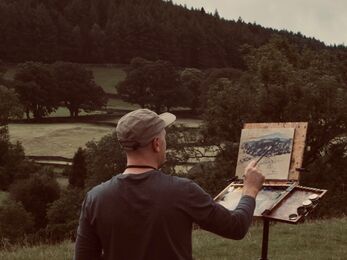 Artist outdoors painting a scene