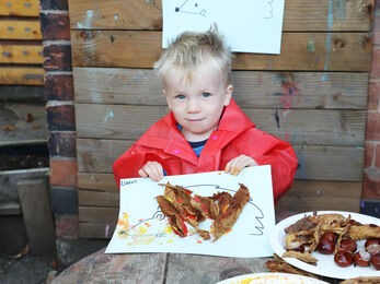 Child holding up their natural artwork