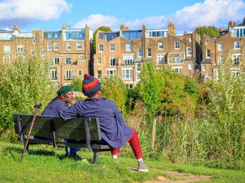 Two people sat on a bench in an urban park, talking