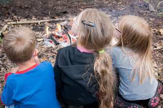 children sitting by fire