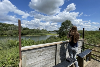 Woman standing at a viewing screen with binoculars 