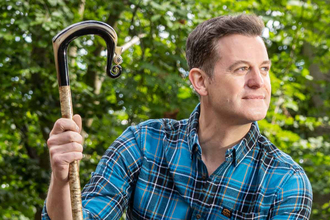 Matt Baker sitting on logs in woods