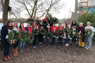 Participants in a Christmas wreath workshop showing the wreaths they made