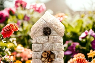 Carved concrete bee and bug home in a garden setting