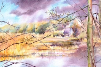 Autumnal scene of a lake with reeds, fields and a house beyond. Trees with no leaves are in the foreground