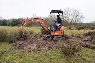 Man in orange digger in a meadow