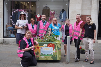 Group of people in high vis vests around a planter full of flowers in Nottingham