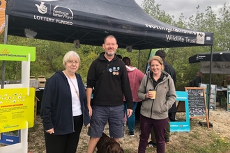 Three NWT staff stand in front of Nottinghamshire Wildlife Trust stand at event
