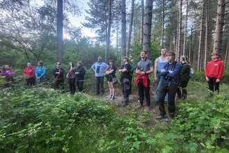Young volunteers in the woods listening to a guide