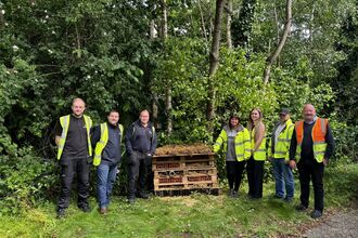 Volunteers next to a bug hotel