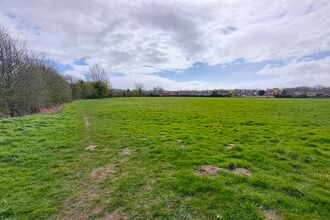 View across a large field with trees and houses in background