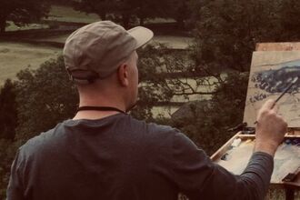 Artist outdoors painting a scene