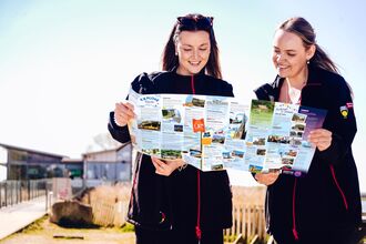 Two ladies looking at a bus guide infront of a building on a nature reserve