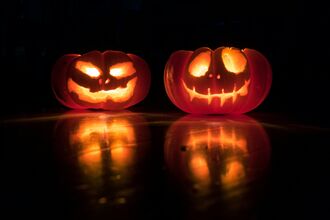 Two carved halloween pumpkins lit up at night
