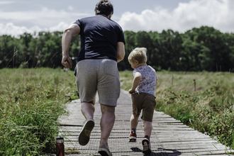 Adult and child running away from the camera along a wooden boardwalk