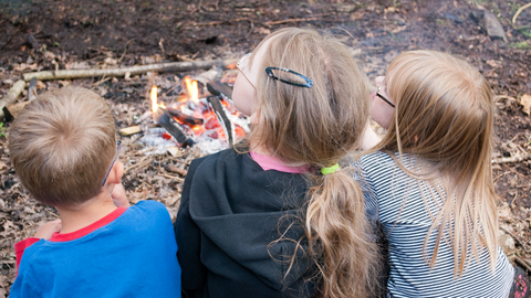 children sitting by fire
