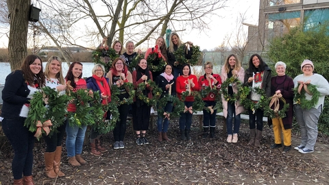 Participants in a Christmas wreath workshop showing the wreaths they made