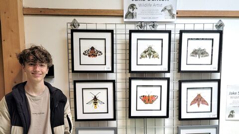 Photo of Jake Sexton next to an exhibition of his art