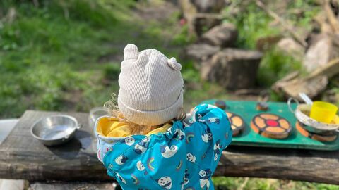 Small child in forest with kitchen toys
