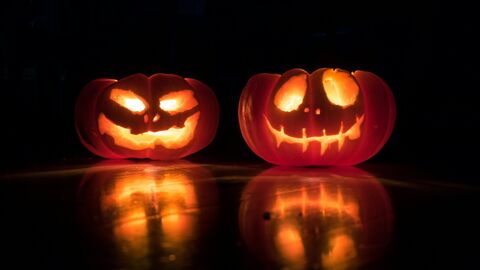 Two carved halloween pumpkins lit up at night
