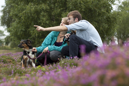 Dog on lead in heathland with couple