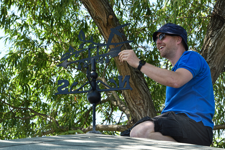 Man on roof with new weathervane 