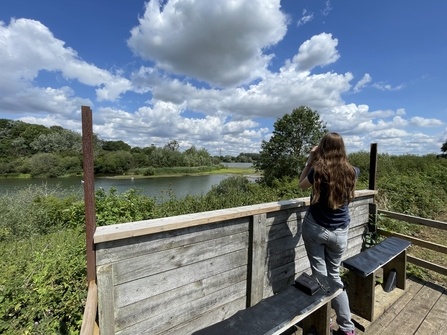 Woman standing at a viewing screen with binoculars 