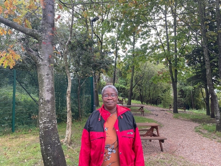Woman in red coat standing in the woods near benches