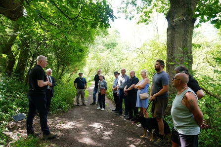 People gathered in woodland path listening to a speech