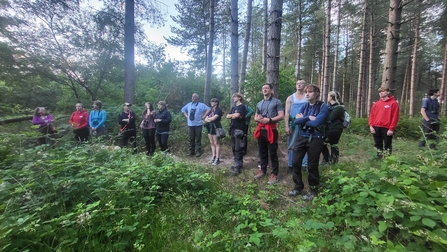 Young volunteers in the woods listening to a guide