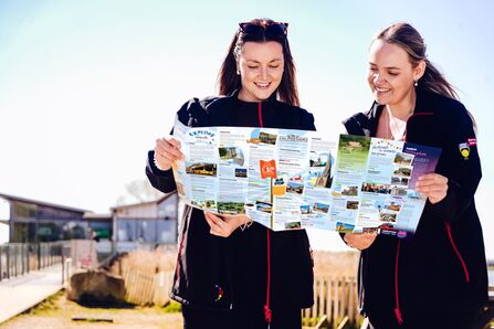 Two ladies looking at a bus guide infront of a building on a nature reserve