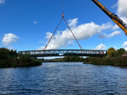 Bridge across pond held in place with crane