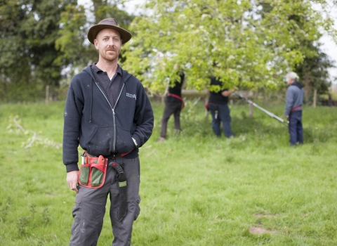 Laurence standing in an orchard