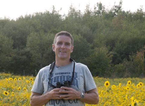 Iolo stands in a field of sunflowers