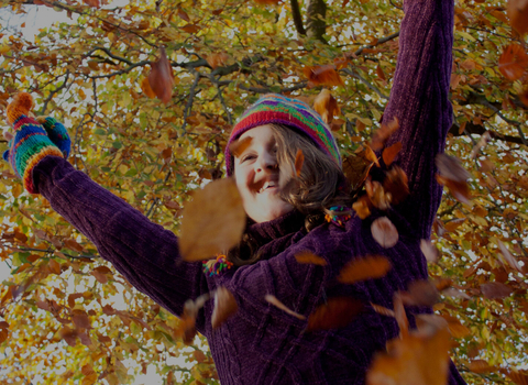 Kid playing in autumn leaves
