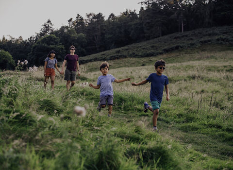 Family with kids running through field